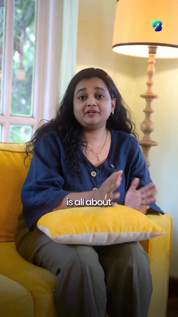 A representative of ACN Silks & Fashions speaking to camera on a yellow sofa