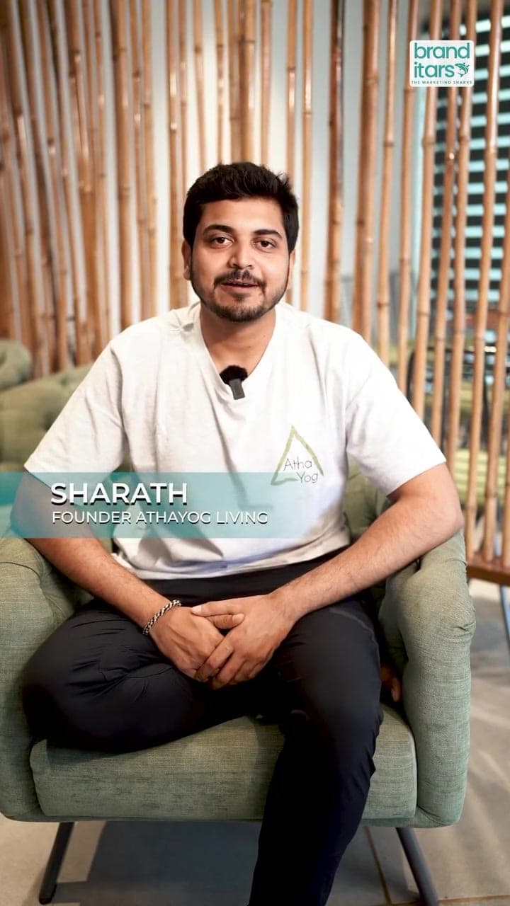 Sharath, founder of AthaYog Living, speaking to camera from a green armchair