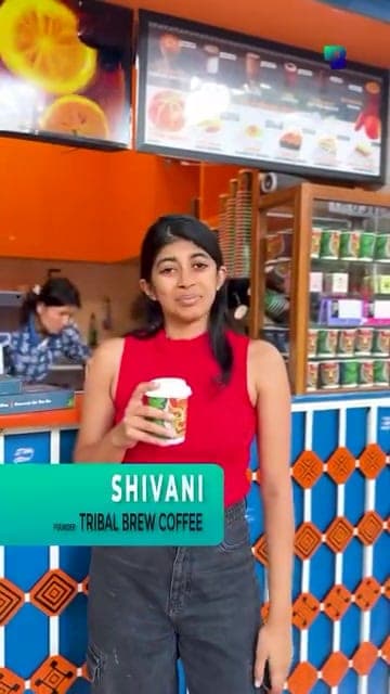 Shivani, founder of Tribal Brew Coffee, holding a cup at her café counter